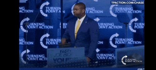 a man in a suit and tie stands in front of a sign that says turning point action
