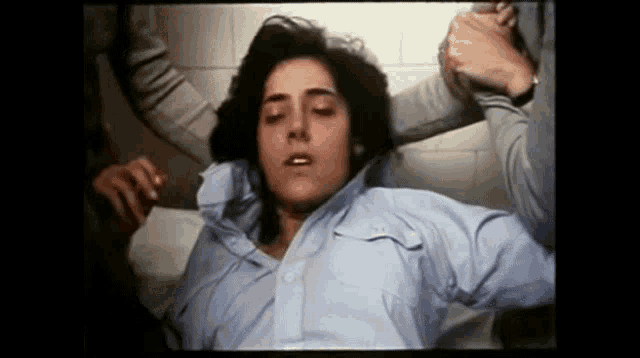 a woman in a blue shirt is laying on a bed