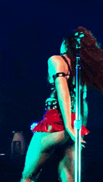 a woman in a red skirt is dancing on stage in front of a microphone