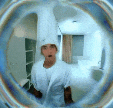a man wearing a white shirt and a white hat stands in a room