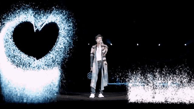 a man singing into a microphone in front of a heart made of water