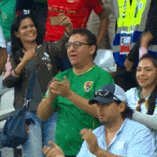 a man in a green shirt applauds in a crowd of people