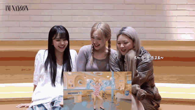 three girls are sitting in front of a screen that says im nayeon