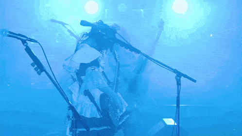 a woman playing a guitar in front of a microphone in a blue light