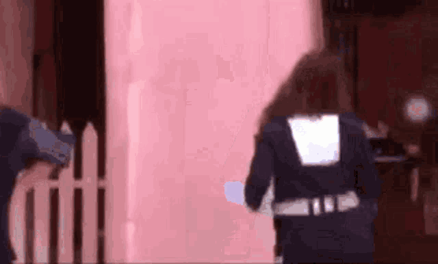 a man in a blue uniform is standing in front of a pink wall .
