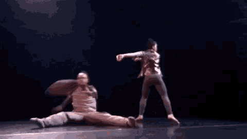 a couple of people are dancing on a stage in the dark