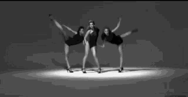three women are dancing in a black and white video .