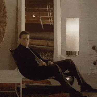 a man in a suit and tie sits on a chair