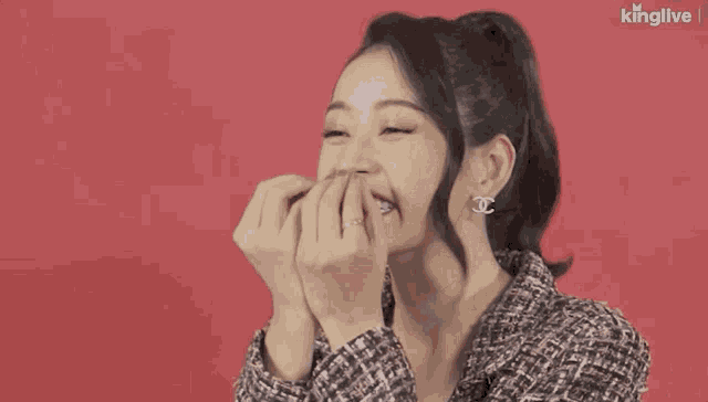 a woman wearing chanel earrings and a ring covering her mouth