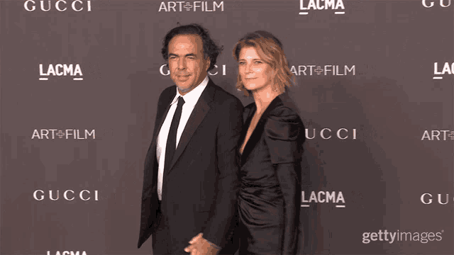 a man and woman are standing in front of a wall that says gucci and lacma