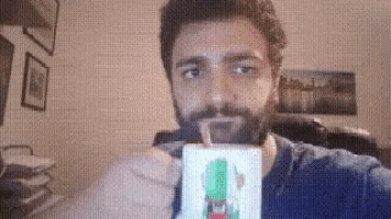 a man with a beard is drinking from a cup with a rocket on it