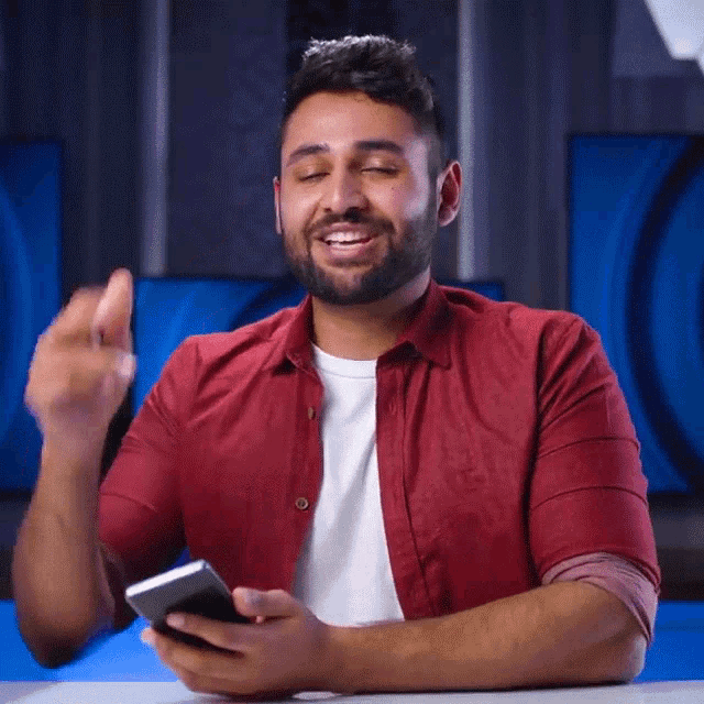 a man in a red shirt is using a cell phone