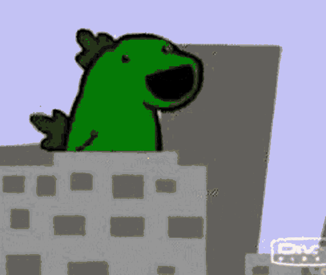 a green dinosaur is standing on top of a building in a city .