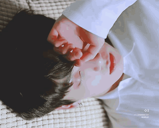 a close up of a person laying on a couch with a white shirt on