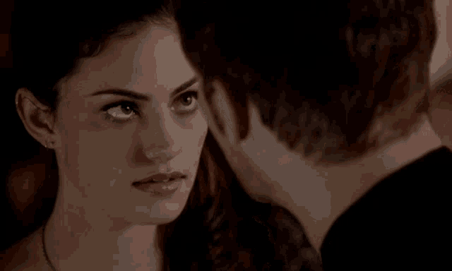 a man and a woman are looking at each other in a dark room .
