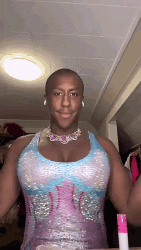 a man wearing a pink and blue dress and a necklace