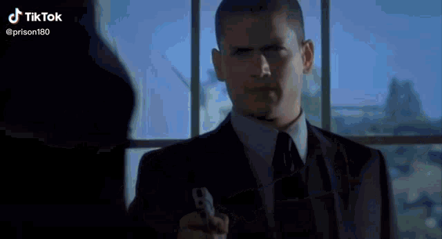 a man in a suit and tie is holding a gun in his hand .