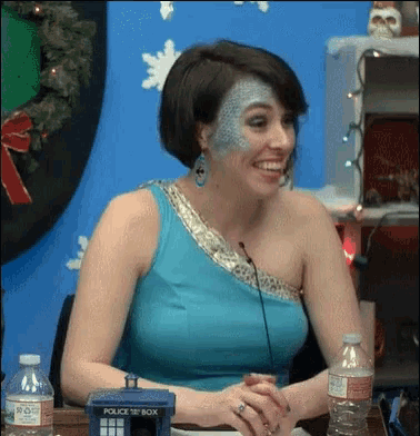 a woman in a blue dress is sitting at a table with a police box in front of her