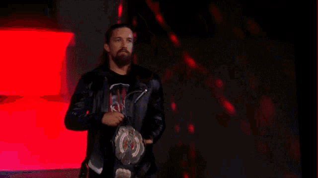 a man in a leather jacket is standing on a stage in front of a large screen with the word y on it .