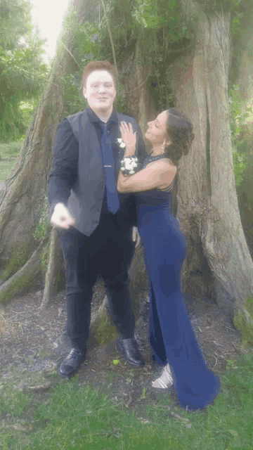 a woman in a blue dress is hugging a man in a suit