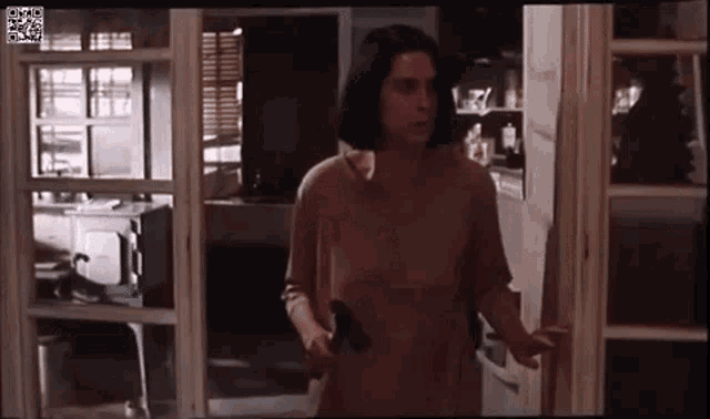 a woman is holding a gun and walking through a door