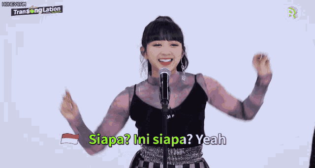 a girl singing into a microphone with the words " siapa ini siapa yeah " on the screen
