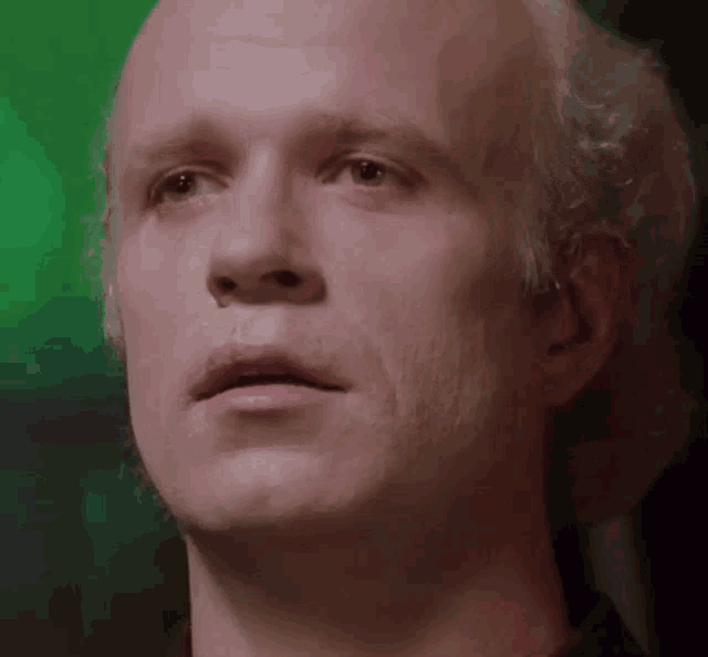 a close up of a man 's face with white hair and a green background