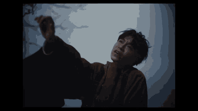 a man in a brown coat is reaching up into the air