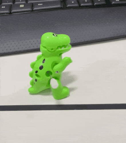 a green toy dinosaur with black spots on it