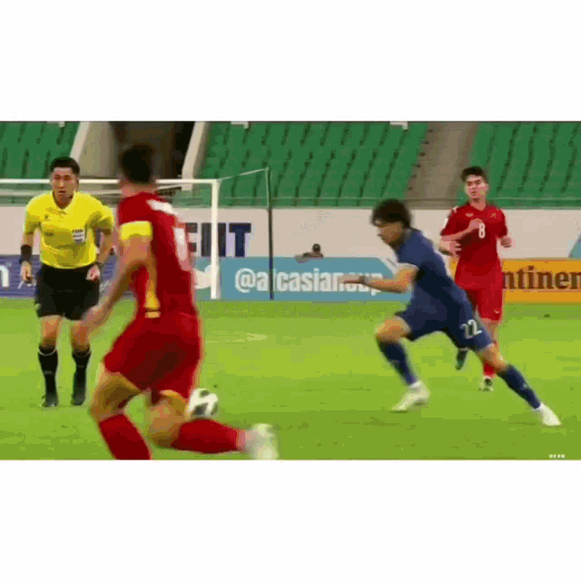 a group of soccer players are playing soccer on a field with a referee in the background .