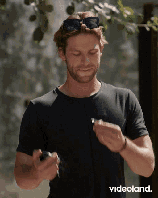 a man wearing sunglasses and a black t-shirt is holding a lighter in his right hand