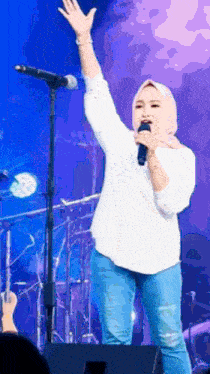 a woman singing into a microphone with her arm in the air