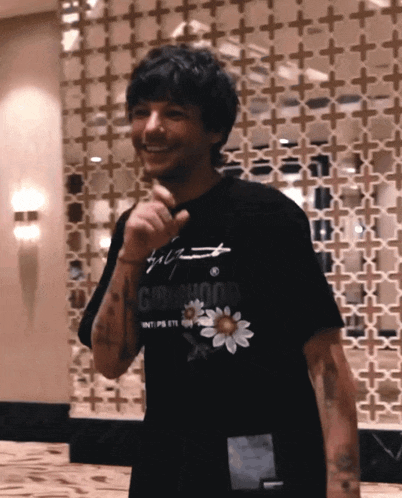 a man wearing a black t-shirt with a flower on it is smiling
