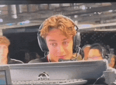 a young man wearing headphones is sitting in front of a computer screen .
