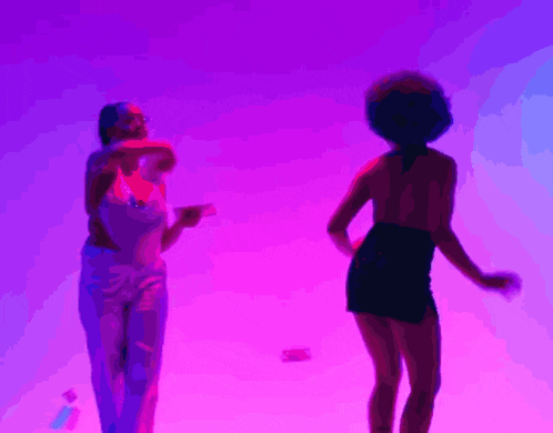 two women are dancing in front of a purple light