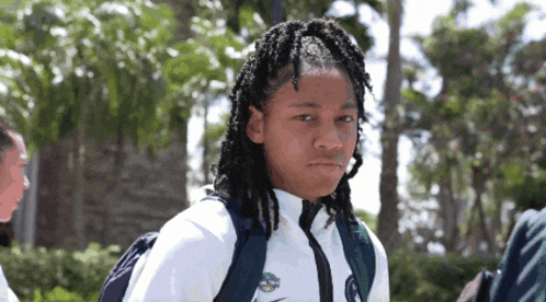a girl with dreadlocks wearing a white nike jacket