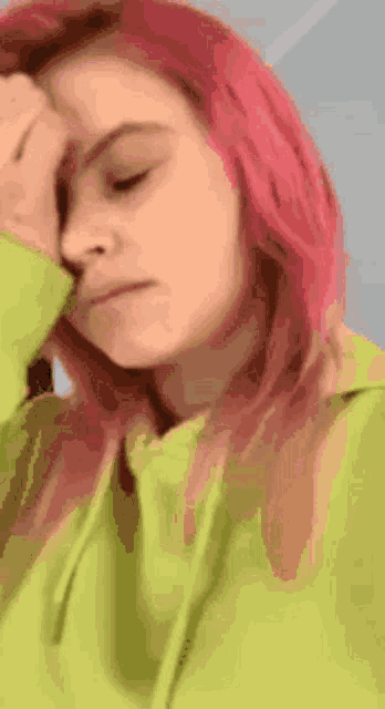 a woman with pink hair is wearing a green hoodie