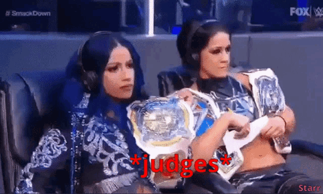 a couple of women sitting next to each other with the word judges in red letters