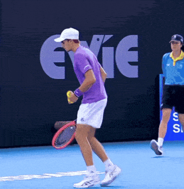 a man in a purple shirt is holding a tennis racquet on a tennis court