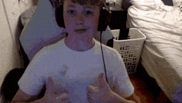 a young boy wearing headphones is giving a thumbs up sign