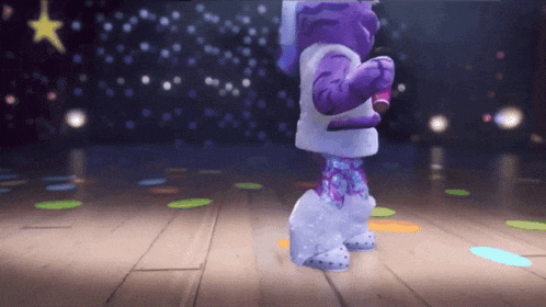 a purple and white cartoon character is dancing on a stage