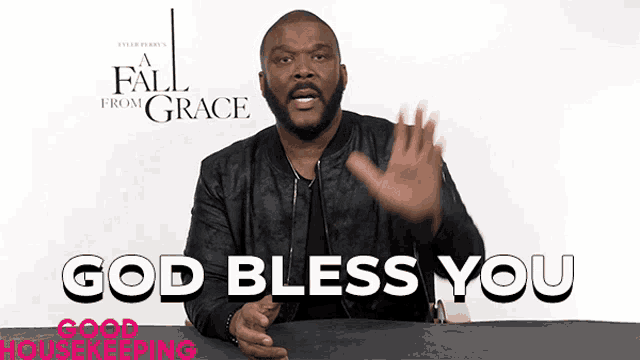 a man in a black jacket says god bless you in front of a fall from grace poster