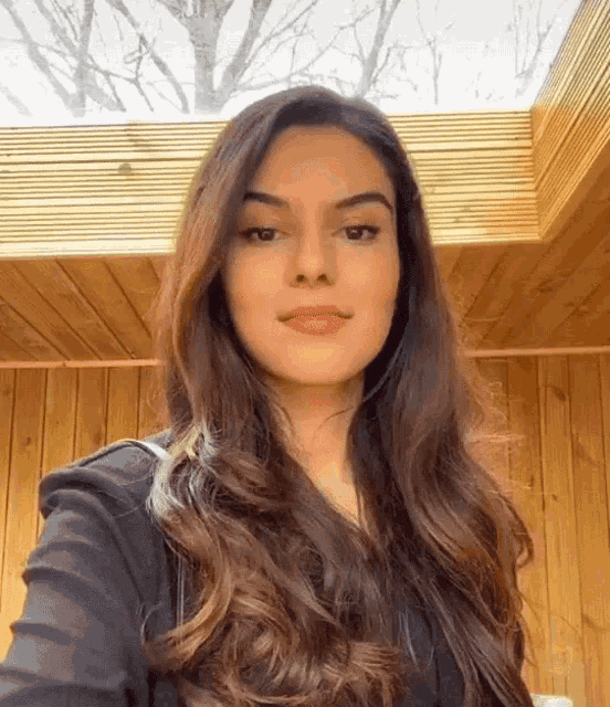 a woman with long dark hair is taking a selfie in front of a wooden ceiling .