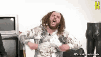 a man with long hair and a beard is making a funny face .