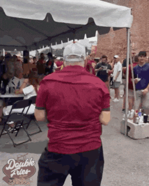 a man in a red shirt is standing in front of a double fries tent