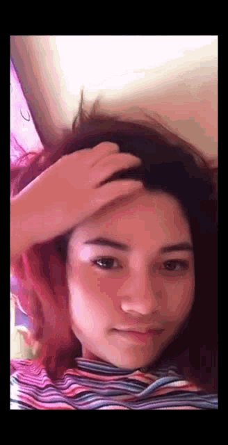 a woman with pink hair is scratching her head with her hand