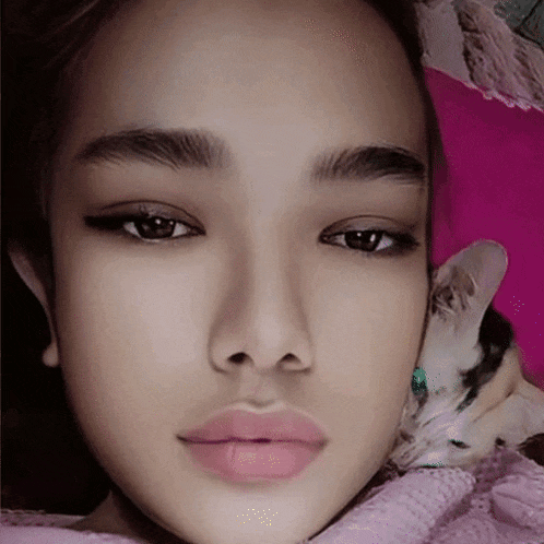 a close up of a woman 's face with a cat in her lap