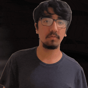 a man with glasses and a beard is pointing at the camera