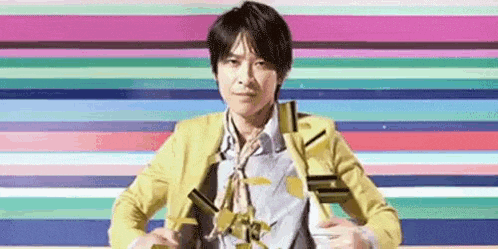 a man in a yellow jacket is standing in front of a colorful striped background .