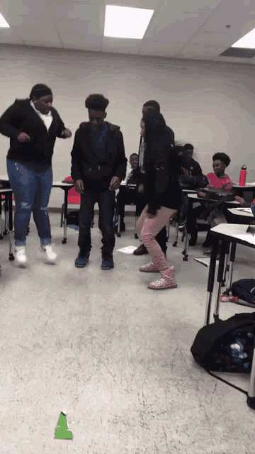 a group of people dancing in a classroom with a green cone in the middle